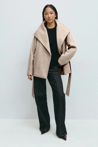 Detail showing high-quality oatmeal wool coat with waist belt and minimalist lapel design