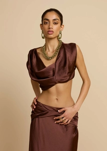 Detail eines dunkelbraunen Satin-Zweiteilers mit plissiertem Crop-Top und Minirock
