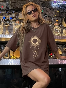 Brown oversized t-shirt with golden sun and moon print in industrial studio setting