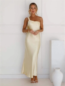 Robe longue élégante en satin champagne avec épaule dénudée et fente dans un studio épuré