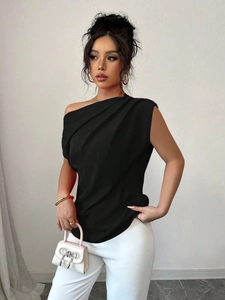 Détail du haut noir à une épaule montrant la texture plissée et l'élégante coupe asymétrique