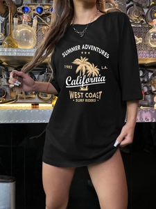 Detail of California surf print on a loose black cotton T-shirt in industrial setting