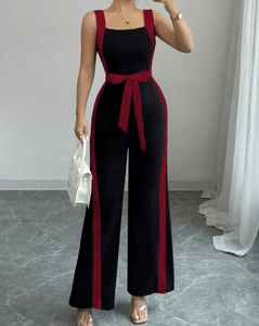 Detail shot of black jumpsuit featuring contrast red side stripes and tied waist belt