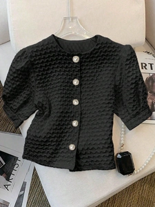 Detail view of black textured short sleeve shirt featuring pearl buttons and puff sleeves