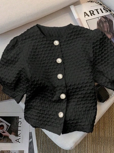 Detailed close-up of textured seersucker fabric and pearl buttons on black shirt
