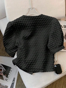 Detailed view of black textured bubble fabric and irregular hem on a chic summer top