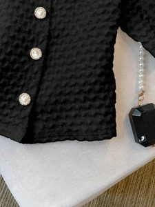 Detailed shot of white textured fabric with elegant gold-rimmed pearl buttons on a blouse