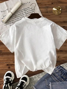 Women's white casual cotton T-shirt flat lay with denim shorts on wooden background