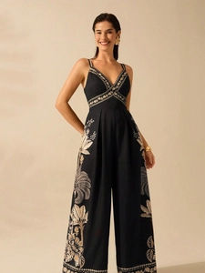 Elegant black V-neck sleeveless jumpsuit with beige tropical floral patterns and wide legs