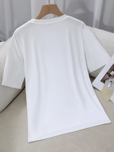 Minimalist white crew neck short sleeve T-shirt shown from the back in a cozy home setting