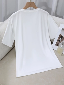 Detailopname van wit katoenen T-shirt met ronde hals aan houten hanger op zachte achtergrond