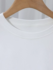 Detailopname van de witte ronde hals van een T-shirt met dubbele stiksels en ribgebreide details
