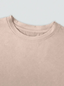 Detailed view of the reinforced double-stitched crew neck on a beige cotton t-shirt
