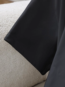 Detailed close-up of smooth black fabric with professional stitching on short sleeve cuff