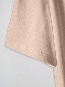Detailed macro view of the double-stitched hem on light apricot knitted cotton sleeves