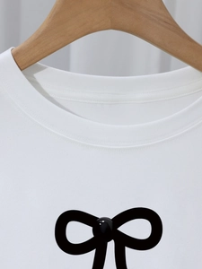 White crew neck T-shirt featuring a black bow design and soft cotton texture