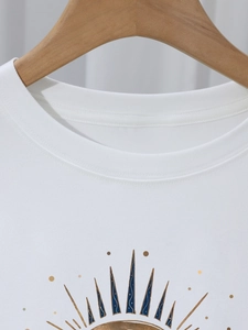 Détail du col rond et de l'imprimé soleil sur un t-shirt blanc à manches courtes