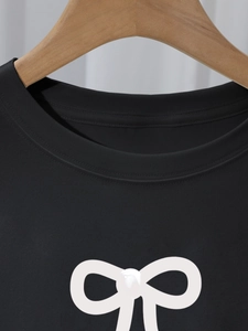Detail of crew neck black T-shirt with white bow print and pearl embellishment