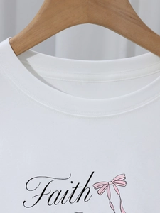 Détail d'un t-shirt blanc en coton avec texte Faith noir et ruban rose graphique