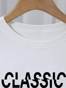 White crew neck cotton T-shirt with classic letter print on a wooden hanger