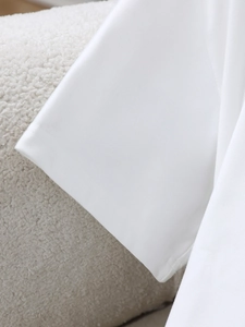 Detailed close-up of sewing craftsmanship on white cotton t-shirt with soft texture