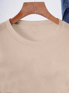 Detail of beige crew neck t-shirt featuring double-stitched collar and soft cotton texture
