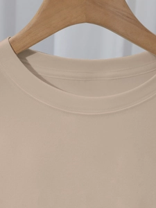 Detail van de versterkte ronde hals en fijne gebreide textuur op een licht kaki t-shirt