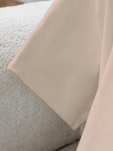 Detail van de lichtbeige T-shirtmouw met fijne stiksels en gladde stoftextuur