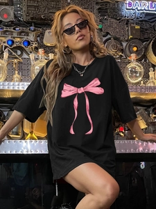 T-shirt noir oversize en coton avec imprimé nœud rose dans un décor industriel chic
