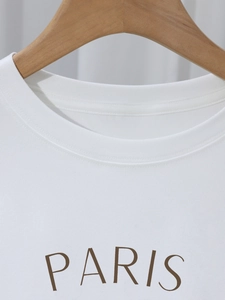 Close-up of the round neckline and PARIS letter print on a white cotton T-shirt