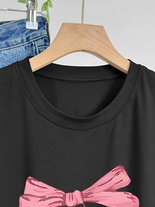 Détail d'un t-shirt noir en coton avec imprimé nœud rose et col rond classique