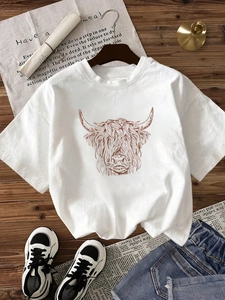 White crew neck cotton T-shirt featuring a brown Highland cow line art graphic on dark wood
