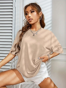Detail of oversized beige crewneck T-shirt with soft fabric texture and natural lighting