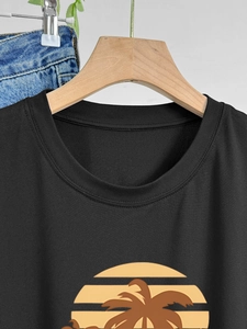 Detail of crew neck stitching and sunset palm tree print on black cotton t-shirt