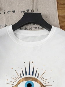Detail of white cotton t-shirt featuring an artistic blue and gold eye graphic print