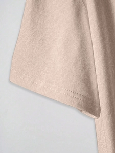 Détail de l'ourlet à double surpiqûre sur la manche d'un t-shirt beige à manches courtes