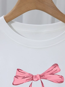 Détail du col côtelé et de l'imprimé nœud rose sur un t-shirt en coton blanc