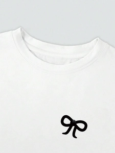 Detail eines weißen Baumwoll-T-Shirts mit schwarzer Schleife und glänzender Perle