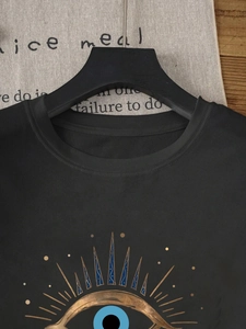 Detail shot of black crewneck T-shirt with mystic sun and eye print on cotton fabric