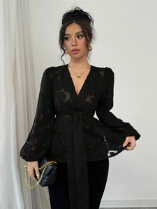 Detailed view of black V-neck blouse featuring semi-transparent floral burnout fabric