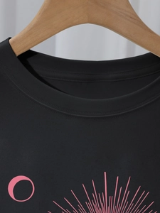 Detail of crew neck stitching and pink abstract graphic print on black cotton t-shirt