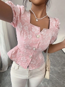 Dettaglio del tessuto jacquard rosa con maniche a sbuffo e bottoni di perla su top a collo quadro