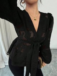 Detail of black semi-transparent wrap top with burnout floral patterns and deep V-neck