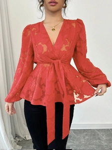 Detail of red floral burnt-out fabric on a wrap V-neck blouse with elegant puff sleeves