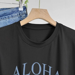Dettaglio della stampa ALOHA su una t-shirt nera in cotone con cuciture pulite sullo scollo