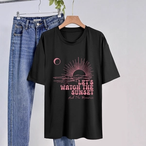 Dettaglio di maglietta in cotone con grafica tramonto rosa e slogan artistico curato