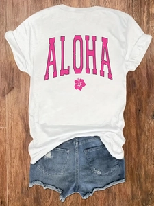 T-shirt bianca con stampa ALOHA e pantaloncini di jeans usurati su fondo in legno