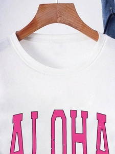 T-shirt blanc à col rond et manches courtes en coton avec imprimé ALOHA rose sur un cintre