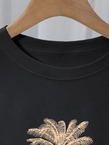 Detail of round neckline and orange palm tree print on black cotton t-shirt