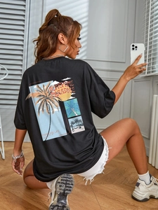 Close-up of tropical palm tree and sunset print on the back of this loose black t-shirt